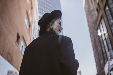 Woman with hat dressed in black walking in the city - KMKF00134
