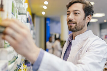 Pharmacist taking medicine from shelf in pharmacy - MFF04283