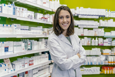 Portrait of smiling pharmacist at shelf with medicine in pharmacy - MFF04290