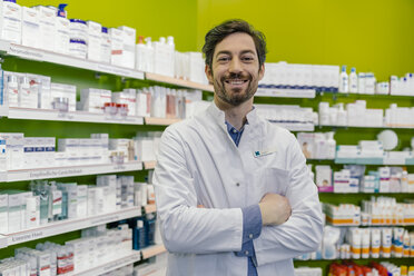 Portrait of smiling pharmacist at shelf with medicine in pharmacy - MFF04291