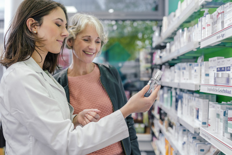 Pharmacist advising customer with cosmetics in pharmacy stock photo