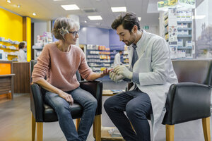 Apothekerin misst Blutzucker eines Kunden in der Apotheke - MFF04299