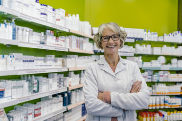 Portrait of smiling pharmacist at shelf with medicine in pharmacy - MFF04306
