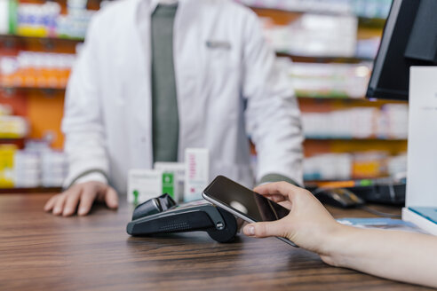 Close-up of customer paying cashless with smartphone in a pharmacy - MFF04324