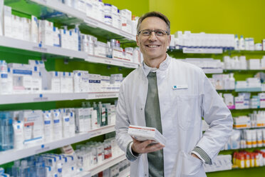 Portrait of smiling pharmacist holding medicine in pharmacy - MFF04337