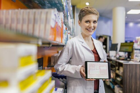 Porträt einer lächelnden Apothekerin in einer Apotheke, die ein Tablet mit einem digitalen Rezept hält - MFF04348