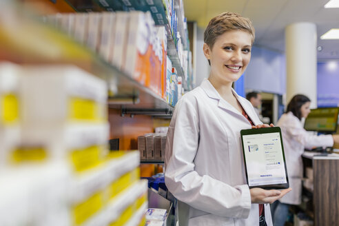 Porträt einer lächelnden Apothekerin in einer Apotheke, die ein Tablet mit einer digitalen Bestellung hält - MFF04349