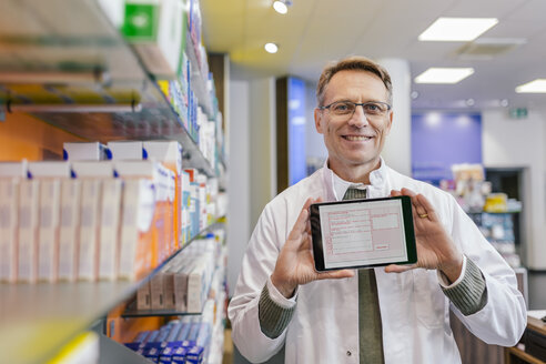 Porträt einer lächelnden Apothekerin in einer Apotheke, die ein Tablet mit einem digitalen Rezept hält - MFF04351