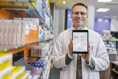 Portrait of smiling pharmacist in pharmacy holding tablet with digital order stock photo