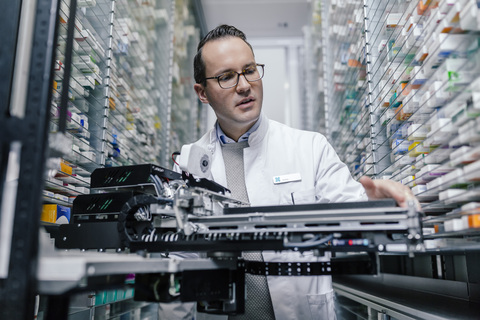 Apotheker bei der Prüfung einer Kommissioniermaschine in der Apotheke, lizenzfreies Stockfoto