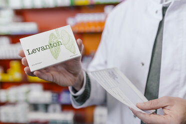 Pharmacist holding tablet package and prescription in pharmacy - MFF04365