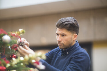 Portrait of man looking at Christmas decoration in a shopping mall - SGF02136