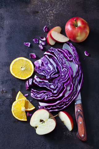 Geschnittener Rotkohl, Äpfel und Orangenscheiben auf dunklem Grund, lizenzfreies Stockfoto