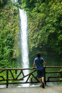 Costa Rica, Arenal Volcano National Park, Man looking at the waterfall of La Fortuna - KIJF01854