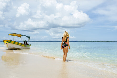 Panama, Bocas del Toro, Cayo Zapatilla, Frau von hinten am Strand mit einem vertäuten Boot - KIJF01870