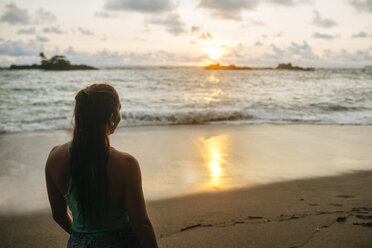 Costa Rica, Frau beobachtet den Sonnenuntergang am Strand von Corcovado - KIJF01892