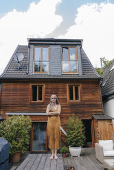 Frau steht auf der Terrasse ihres Hauses - KNSF03458