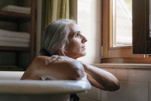 Porträt einer nachdenklichen Frau in der Badewanne mit Blick aus dem Fenster - KNSF03483