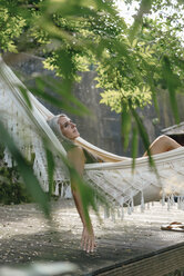 Nachdenkliche Frau entspannt sich in der Hängematte im Garten - KNSF03504