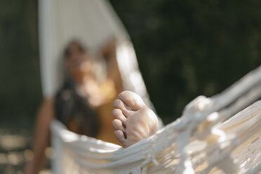 Fuß einer Frau, die sich in einer Hängematte im Garten entspannt, Nahaufnahme - KNSF03505