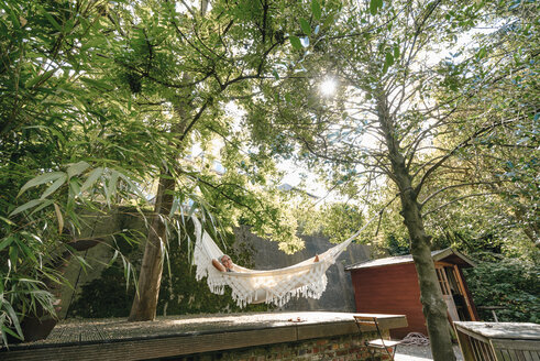 Woman relaxing in hammock in the garden - KNSF03507