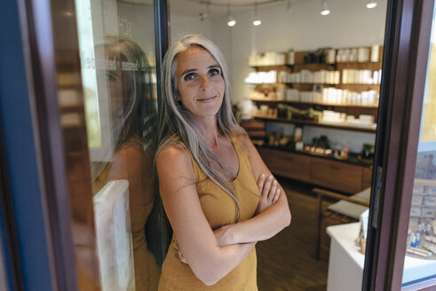 Porträt einer lächelnden Geschäftsfrau am Eingang ihres Ladens - KNSF03513