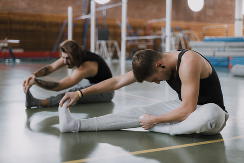 Two young men stretching in gym stock photo