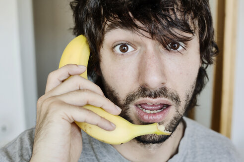 Portrait of astonished young man telephoning with banana - JATF00977