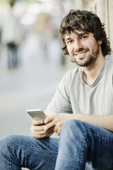 Portrait of smiling young man with cell phone outdoors - JATF00979