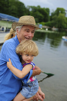 Kleines Mädchen auf den Armen ihres Großvaters am Seeufer - ECPF00163