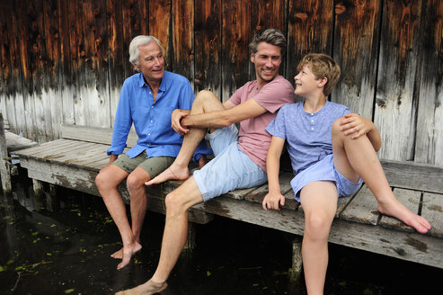 Junge sitzt mit Großvater und Vater zusammen auf dem Steg im Sommer - ECPF00169