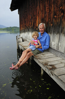 Little girl sitting with grandfather on jetty in summer - ECPF00171