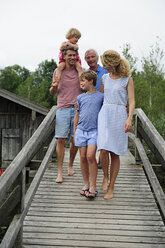 Glückliche Familie beim gemeinsamen Spaziergang auf der Strandpromenade im Sommer - ECPF00173