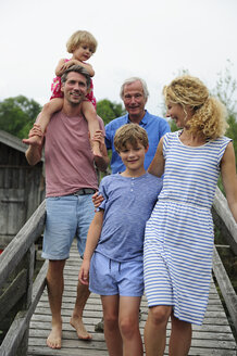 Glückliche Familie beim gemeinsamen Spaziergang auf der Strandpromenade im Sommer - ECPF00174