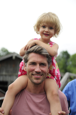 Portrait of happy man carrying his little daughter on shoulders stock photo