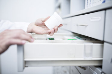 Close-up of pharmacist taking medicine from cabinet in pharmacy - WESTF23909