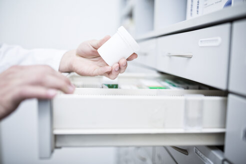 Nahaufnahme eines Apothekers, der Medikamente aus einem Schrank in einer Apotheke nimmt - WESTF23909