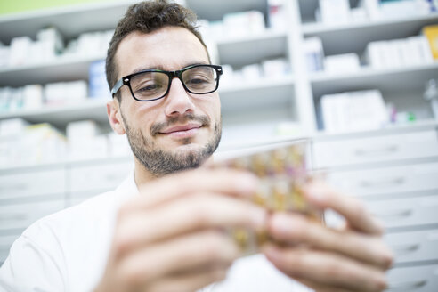 Lächelnder Apotheker mit Tablettenpackung in der Apotheke - WESTF23930