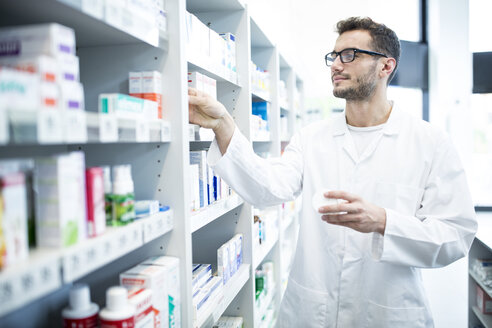 Pharmacist taking medicine from shelf in pharmacy - WESTF23935