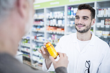 Pharmacist giving pill box to customer in pharmacy - WESTF23939