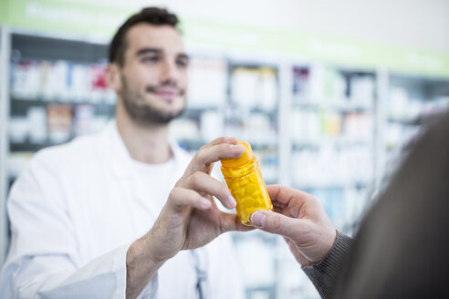 Nahaufnahme einer Apothekerin, die einem Kunden in einer Apotheke eine Pillenschachtel gibt - WESTF23940
