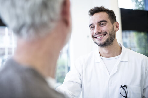 Mann im Arztkittel lächelt den grauhaarigen Mann an - WESTF23942
