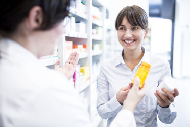 Pharmacist advising customer in pharmacy - WESTF23947