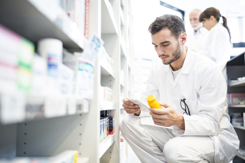 Pharmacist with pill box and prescription in pharmacy stock photo