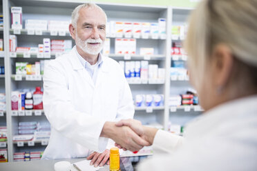 Pharmacist and customer shaking hands in pharmacy - WESTF23965