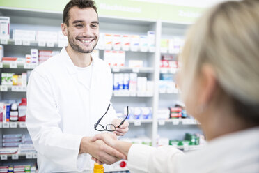 Pharmacist and customer shaking hands in pharmacy - WESTF23967