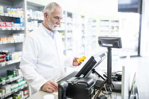 Apothekerin mit Medikamenten am Tresen in der Apotheke, lizenzfreies Stockfoto