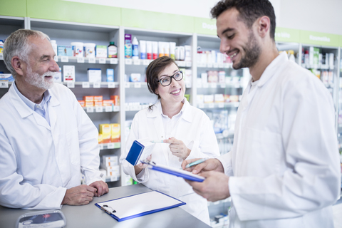 Smiling pharmacists with clipboard at counter in pharmacy stock photo