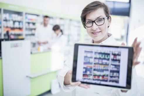 Porträt einer lächelnden Apothekerin in einer Apotheke, die eine Tablet zeigt - WESTF23993