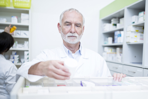 Apothekerin nimmt Arzneimittel aus dem Schrank in der Apotheke, lizenzfreies Stockfoto